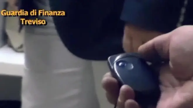 Un'immagine tratta da un video diffuso dalla Guardia di Finanza di Treviso che documenta la scoperta di una sorta di stanza 'segreta', con l'entrata nascosta da un mobile nei locali di due società operanti nel settore del mobile che, tra il 2004 ed il 2011, hanno evaso ricavi per oltre 100 milioni di euro ed IVA per 32 milioni, impiegando irregolarmente 434 lavoratori, di cui 13 completamente in nero. Quando le Fiamme Gialle hanno iniziato le verifiche fiscali presso le aziende hanno notato un cavo elettrico che fuoriusciva dal muro vicino ad un appendiabiti e, nell'altro caso, sempre un appendiabiti attaccato al muro in posizione non utile al suo utilizzo. Insospettiti, i Finanzieri hanno scoperto che i due accessori nascondevano, in realtà, le porte di accesso ai vani in cui era tenuta la vera contabilità delle aziende; in un caso un telecomando faceva scattare una serratura elettromagnetica per l'apertura dell'attaccapanni, che nascondeva una vera e propria stanza, nell'altro caso la chiave di apertura era camuffata dal pomello dell'attaccapanni. ANSA / GDF