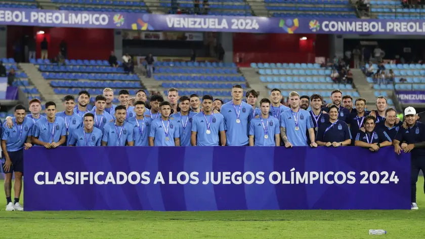 epa11146551 Players of Argentina pose next to a qualifier board to Paris 2024 Olympic Games after winning the second place of the CONMEBOL U-23 Pre-Olympic qualifier soccer match against Venezuela at Brigido Iriarte Stadium in Caracas, Venezuela, 11 February 2024. EPA/RAYNER PENA R.
