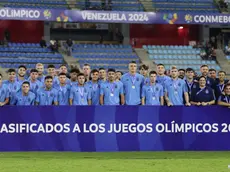 epa11146551 Players of Argentina pose next to a qualifier board to Paris 2024 Olympic Games after winning the second place of the CONMEBOL U-23 Pre-Olympic qualifier soccer match against Venezuela at Brigido Iriarte Stadium in Caracas, Venezuela, 11 February 2024. EPA/RAYNER PENA R.