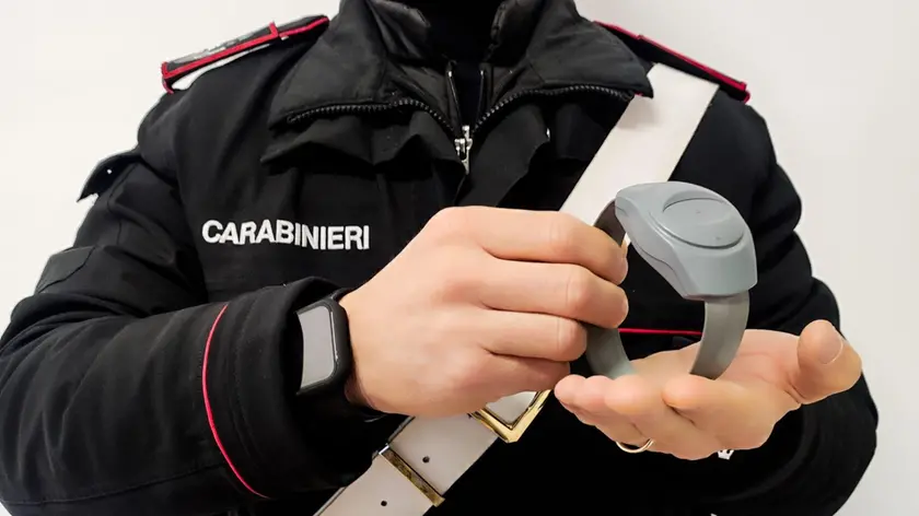 Un carabiniere tiene in mano un braccialetto elettronico