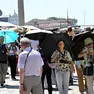 I turisti in piazza San Marco cercano di ripararsi con gli ombrelli. Foto Ansa