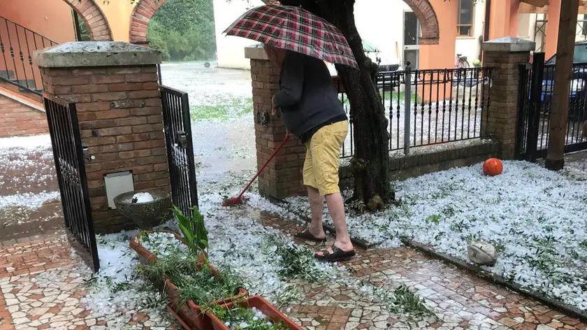 A Rubano un residente spazza la grandine dal vialetto dopo il maltempo