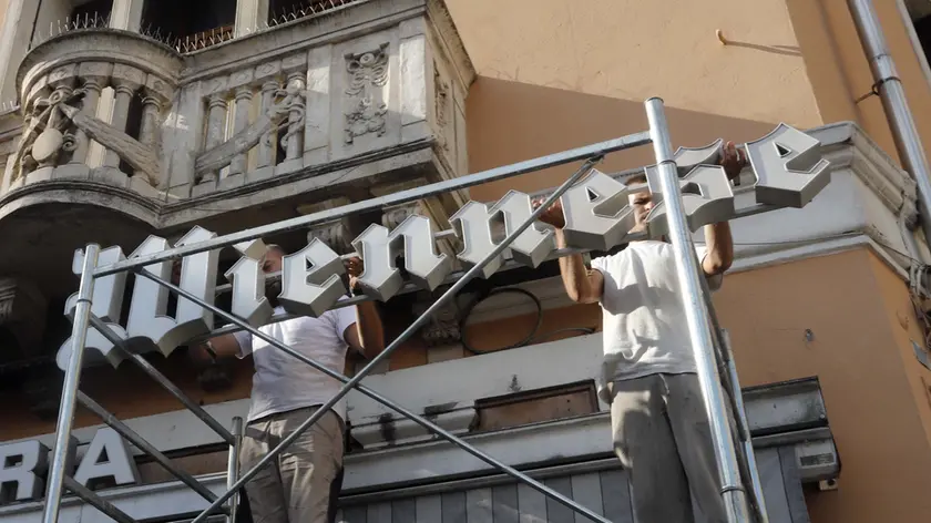 Gli operai che ieri hanno rimontato l’insegna storica della pasticceria Wiennese