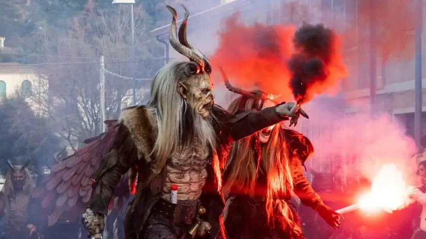 Due Krampus assieme all’angelo nero del gruppo di Merano alle prese con i giochi di fuoco durante una sfilata