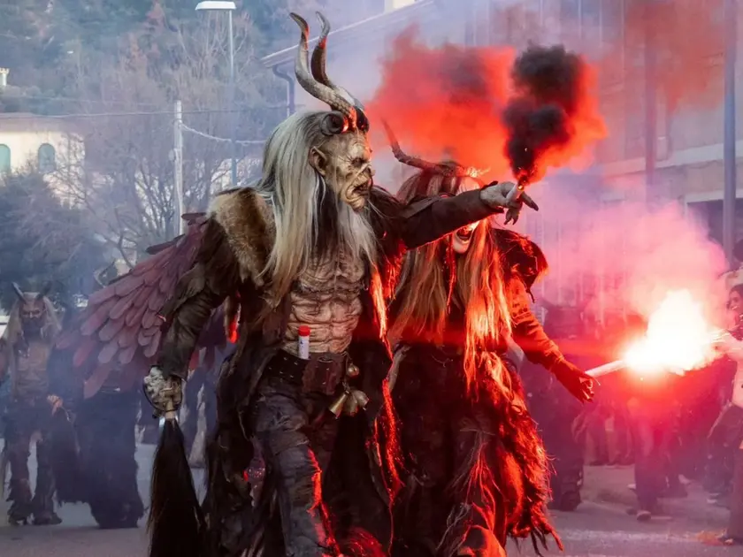 Due Krampus assieme all’angelo nero del gruppo di Merano alle prese con i giochi di fuoco durante una sfilata