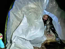 Gli inquilini sorridenti, uno dei fratelli mentre esce dalla sua tenda per rispondere all’intervista e le due sorelle intente a mangiare