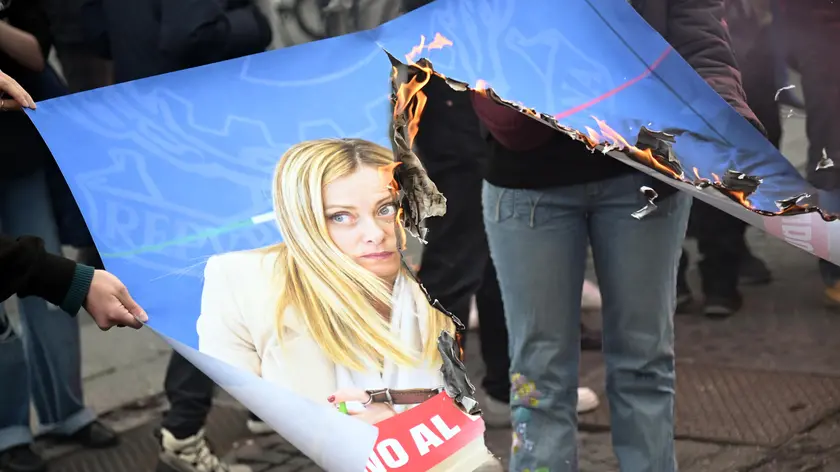 Manifestanti bruciano le foto di Meloni e Nordio durante il corteo a Roma