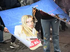 Manifestanti bruciano le foto di Meloni e Nordio durante il corteo a Roma