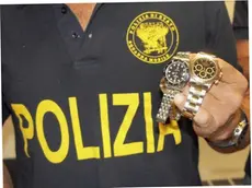 In una foto d'archivio un poliziotto mostra due Rolex recuperati.