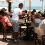 Un lavoratore stagionale mentre serve da bere in un locale in riva al mare