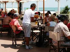 Un lavoratore stagionale mentre serve da bere in un locale in riva al mare