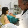 Un medico di medicina generale mentre somministra un vaccino a una paziente nel suo ambulatorio