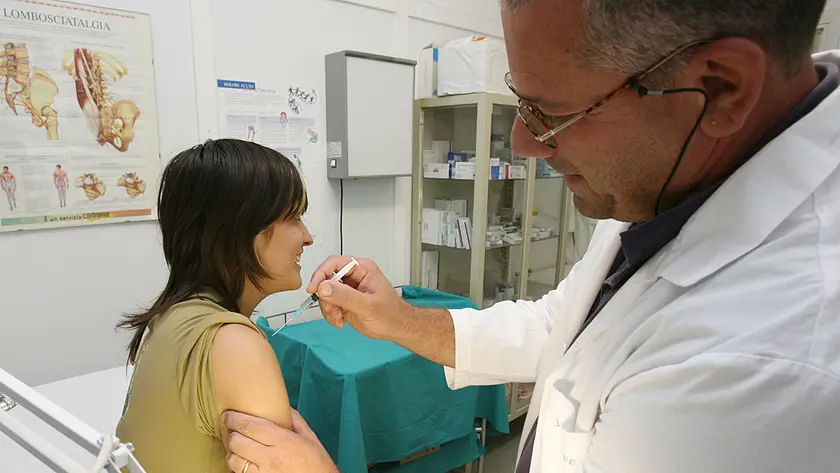 Un medico di medicina generale mentre somministra un vaccino a una paziente nel suo ambulatorio