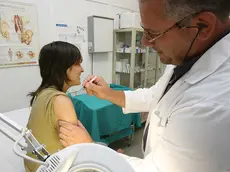 Un medico di medicina generale mentre somministra un vaccino a una paziente nel suo ambulatorio