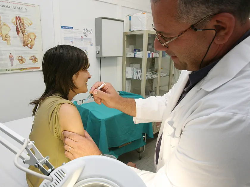 Un medico di medicina generale mentre somministra un vaccino a una paziente nel suo ambulatorio