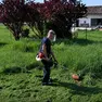 Un uomo al lavoro con il decespugliatore in giardino