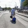 Un passeggero trascina il suo trolley per raggiungere la fermata dei bus sostitutivi
