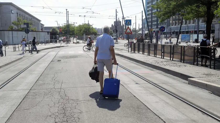 Un passeggero trascina il suo trolley per raggiungere la fermata dei bus sostitutivi