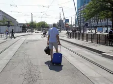 Un passeggero trascina il suo trolley per raggiungere la fermata dei bus sostitutivi