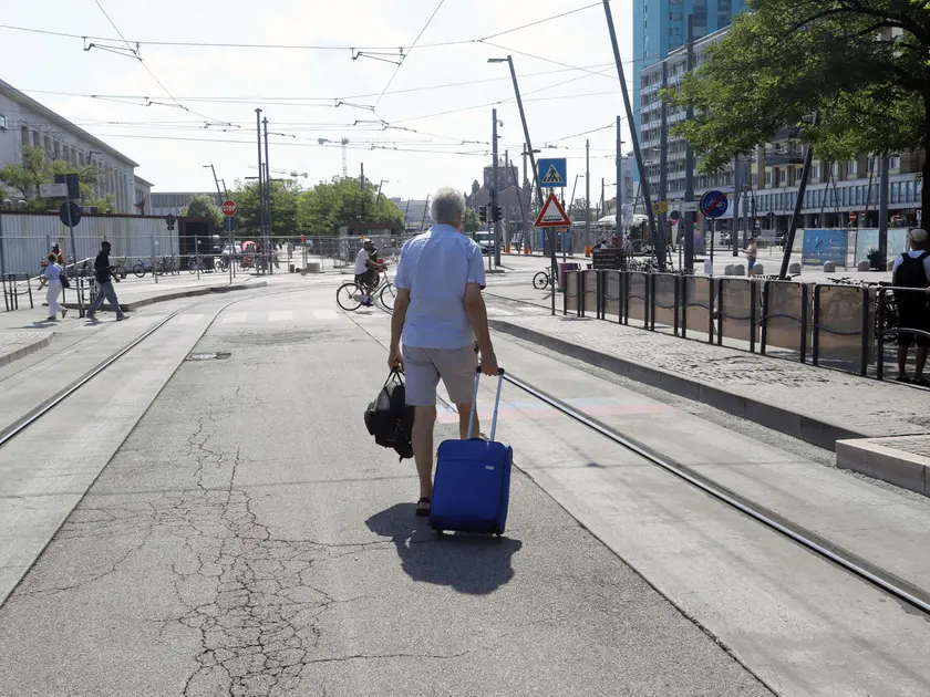 Un passeggero trascina il suo trolley per raggiungere la fermata dei bus sostitutivi