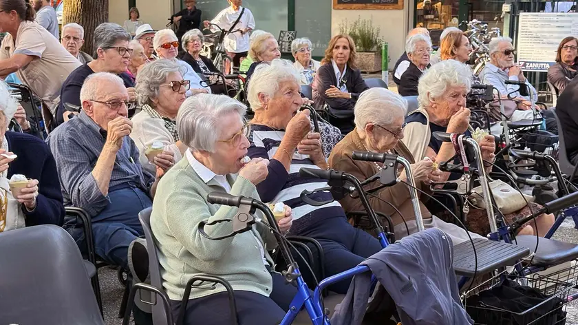 Gli ospiti della casa di riposo mentre mangiano il dolce preparato per l’evento (Foto Bianchi)