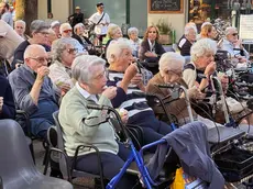 Gli ospiti della casa di riposo mentre mangiano il dolce preparato per l’evento (Foto Bianchi)