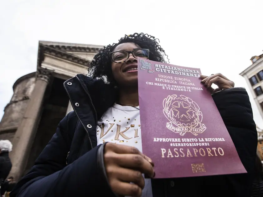 Una donna esibisce un cartello a favore della concessione della cittadinanza
