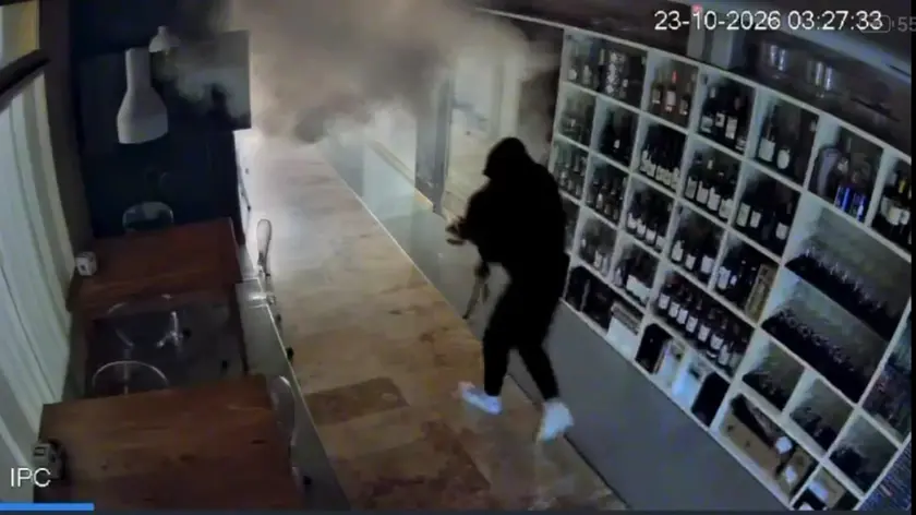 Uno dei ladri in fuga con il bottino nonostante il fumogeno in azione