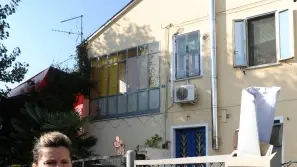 DANIELA DONDU VOINEA. La sua casa al primo piano è preda dell’umidità. A destra: Graziella Aramini mostra il cartello di gratitudine affisso nel salone