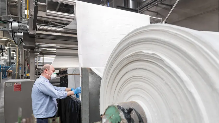 La fabbrica è la stessa ma da un giorno all'altro è cambiato il lavoro. Non più abiti da cucire, libri da stampare, borse da confezionare o capi di alta moda, ma mascherine igieniche per proteggersi e proteggere contro il Covid 19. E' la svolta solidale delle migliaia di lavoratori delle aziende che hanno deciso di cambiare produzione, a volte macchinari spesso materie prime, per dare una mano nell'emergenza coronavirus. Una novità anche per Graziella Balbino che dopo 37 anni di drappeggi e pinces a tailleur e pantaloni, si è trovata a cucire mascherine. "Con i guanti il tessuto all'inizio scivolava, ora mi sono abituata e sono orgogliosa di questo progetto", spiega la responsabile dell'atelier di Alba del gruppo Miroglio. ANSA/UFFICIO STAMPA MIROGLIO +++ ANSA PROVIDES ACCESS TO THIS HANDOUT PHOTO TO BE USED SOLELY TO ILLUSTRATE NEWS REPORTING OR COMMENTARY ON THE FACTS OR EVENTS DEPICTED IN THIS IMAGE; NO ARCHIVING; NO LICENSING +++