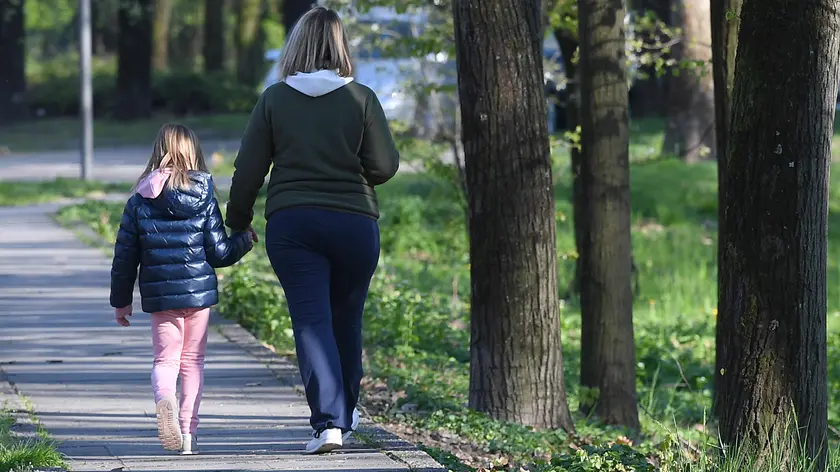 Una madre passeggia con la figlia nelle vicinanze di casa a San Donato Milanese, vicino a Milano, 1 aprile 2020. La circolare diffusa ieri dal Vimilnale che permette a solo genitore di camminare con i figli minori in prossimità della propria abitazione è stata fortremente criticata. ANSA/DANIEL DAL ZENNARO