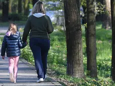 Una madre passeggia con la figlia nelle vicinanze di casa a San Donato Milanese, vicino a Milano, 1 aprile 2020. La circolare diffusa ieri dal Vimilnale che permette a solo genitore di camminare con i figli minori in prossimità della propria abitazione è stata fortremente criticata. ANSA/DANIEL DAL ZENNARO