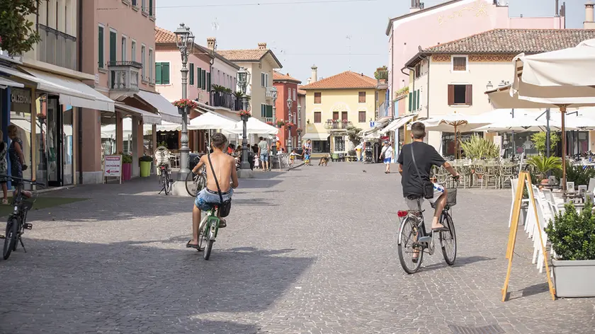 Un ciclista a torso nudo in centro a Caorle (Foto Vianello)