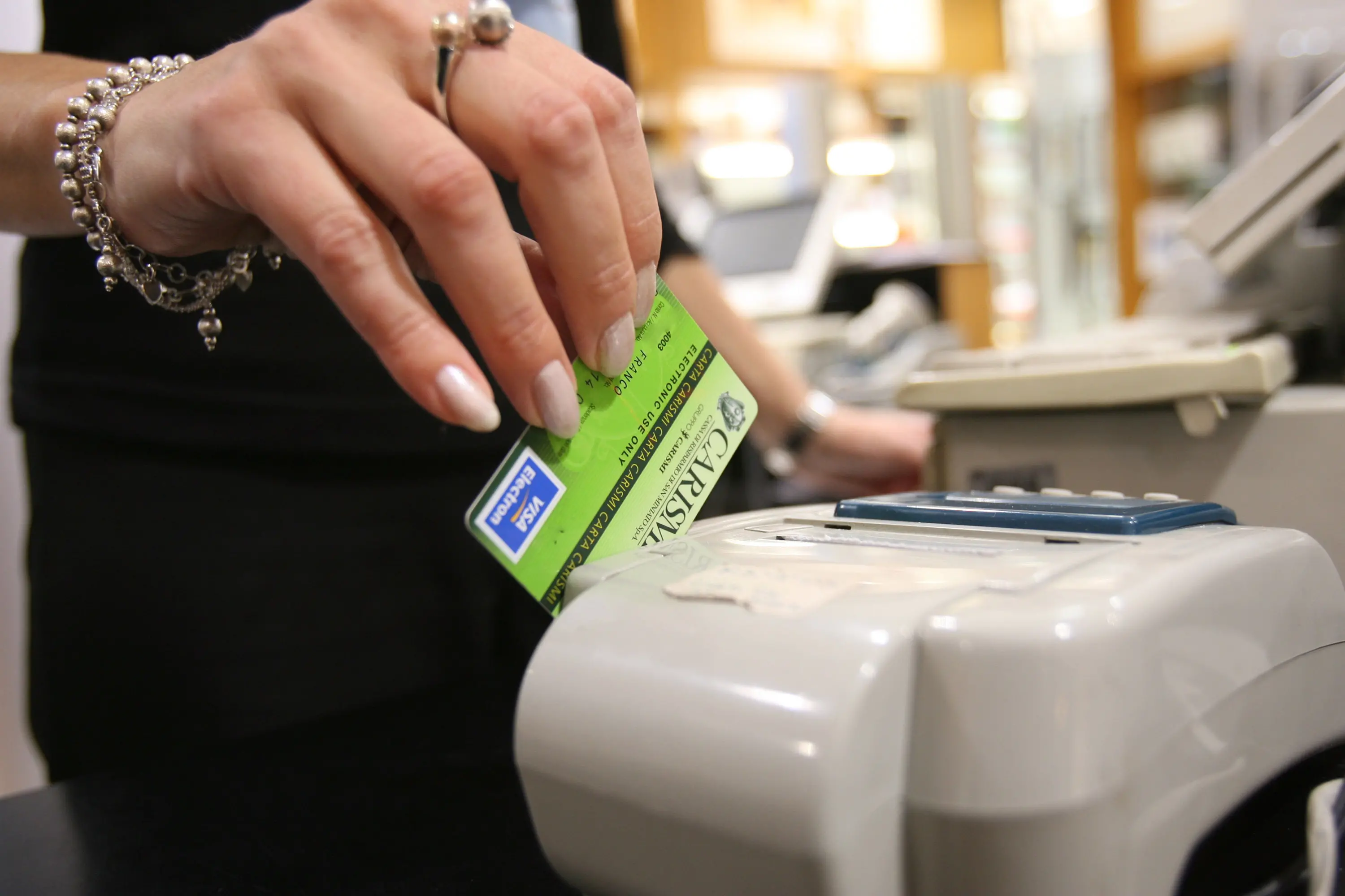 Una donna passa il bancomat per pagare un acquisto in una foto d'archivio. ANSA / FRANCO SILVI