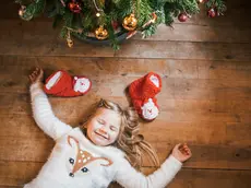 Smiling girl with closed eyes lying under the Christmas tree
