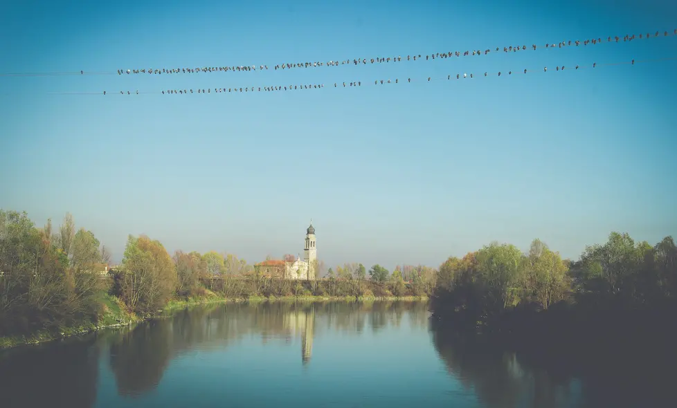 Boara Pisani (PD), 23 novembre 2017. Reportage su Boara Pisani. Nella foto: la chiesa a ridosso del fiume con uccelli sui fili.
