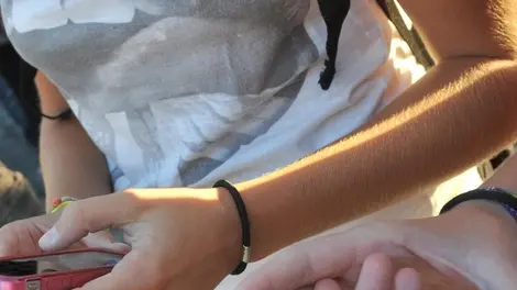 Due ragazze si scambiano messaggi sugli iPhone prima di entrare a scuola.ANSA/FRANCO SILVI