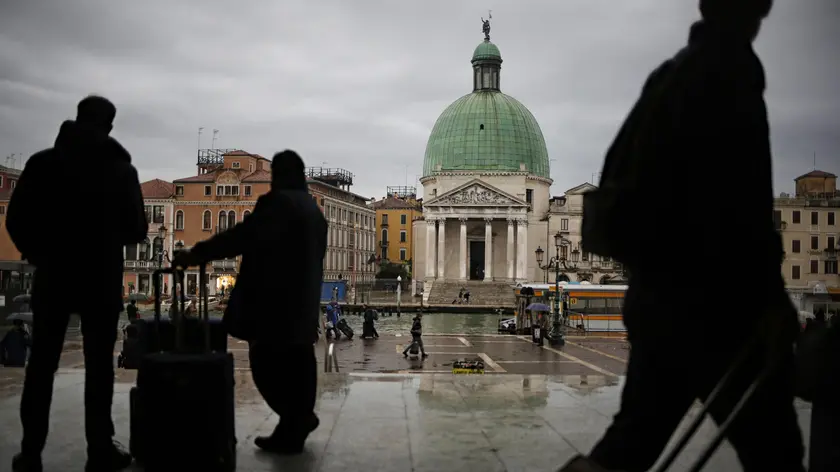 Silhouettes of tourists with their luggage are seen outside the train station in Venice, northern Italy, on November 11, 2016. / AFP / MARCO BERTORELLO (Photo credit should read MARCO BERTORELLO/AFP via Getty Images)