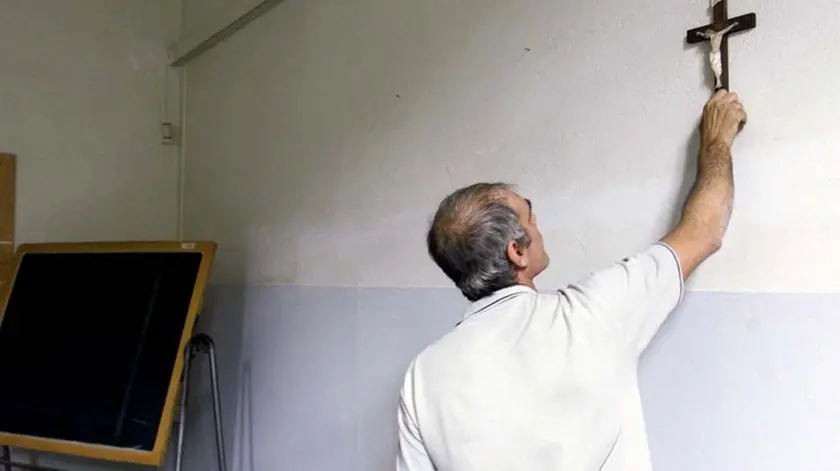Un' immagine di archivio mostra un custode che appende un crocifisso all'interno di un'aula di una scuola. ''Non possono esserci regole su come, quando e se esporre il crocifisso. Questo diritto nessun Tribunale ce l'ho potra' togliere. E' un diritto che nessuno puo' togliere perche' noi rispettiamo il diritto di chi non crede e rivendichiamo il diritto dei credenti di farlo con i loro simbolo''. Lo afferma il ministro degli Esteri Franco Frattini in un passaggio del suo intervento alla tavola rotonda 'Identita' italiana e liberta' della Chiesa' in corso a Orvieto. FRANCO SILVI/ARCHIVIO - ANSA - DBA