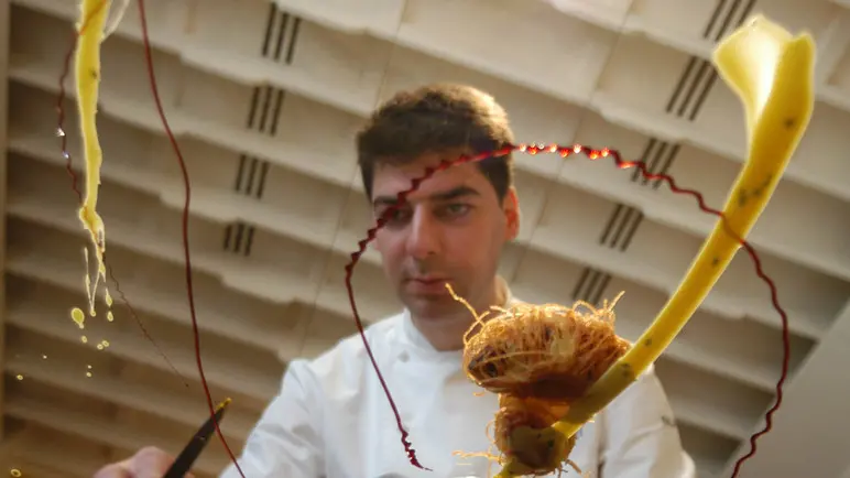 Lo chef Massimiliano Alajmo, il piÃ¹ giovane tre stelle Michelin al mondo mentre crea un suo piatto alle spezie utilizzando una lastra di vetro.