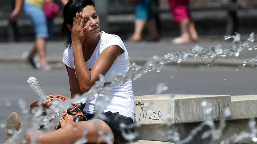 In piazza Castello una turista sfrutta la fontana per combattere il caldo iolento che ha investito la città di Milano, 25 luglio 2013. MATTEO BAZZI/ ANSA
