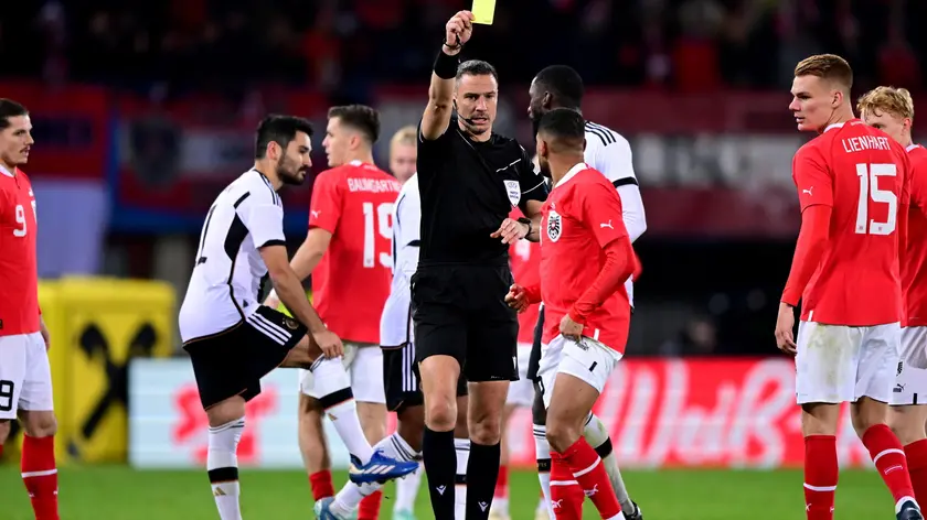 epa10988407 Slowenian referee Slavko Vincic shows a yellow card to Austria's Phillipp Mwene during the international friendly soccer match between Austria and Germany in Vienna, Austria, 21 November 2023. EPA/CHRISTIAN BRUNA