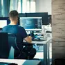 Closeup rear view of a young man coding on multiple computers