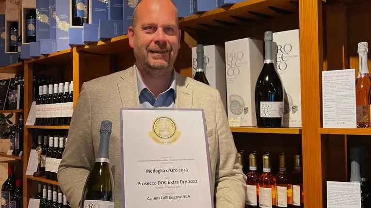Nicola Zandonà mostra l’attesta della medaglia d’oro per il Prosecco doc extra dry 2022. A destra la Cantina Colli Euganei di Vo’