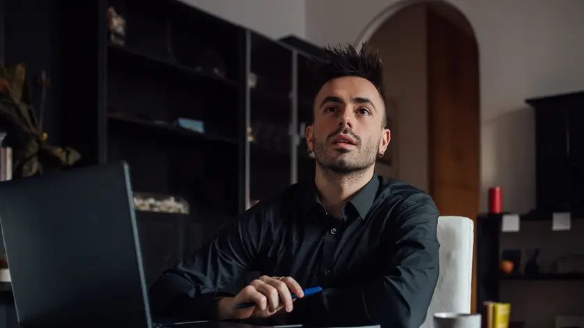 Man looking up while using laptop in home office