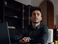 Man looking up while using laptop in home office