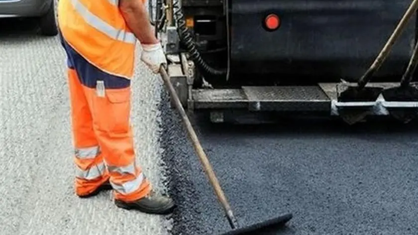 Un operaio impegnato a stendere uno strato di asfalto su una strada