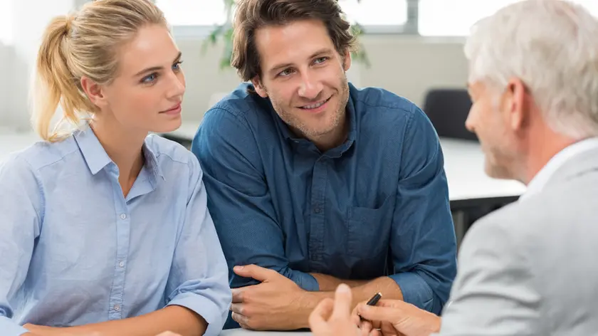 Businessman explaining loan policy to young couple. Happy young couple discussing with a financial agent their new investment. Financial consultant presents bank investments to a young woman and smiling man.