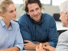 Businessman explaining loan policy to young couple. Happy young couple discussing with a financial agent their new investment. Financial consultant presents bank investments to a young woman and smiling man.