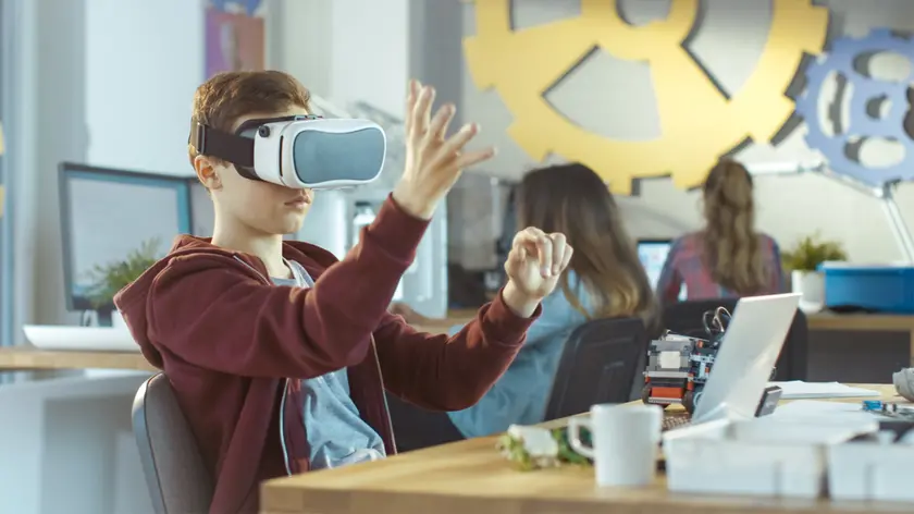 In a Computer Science Class Boy Wearing Virtual Reality Headset Works on a Programing Project.